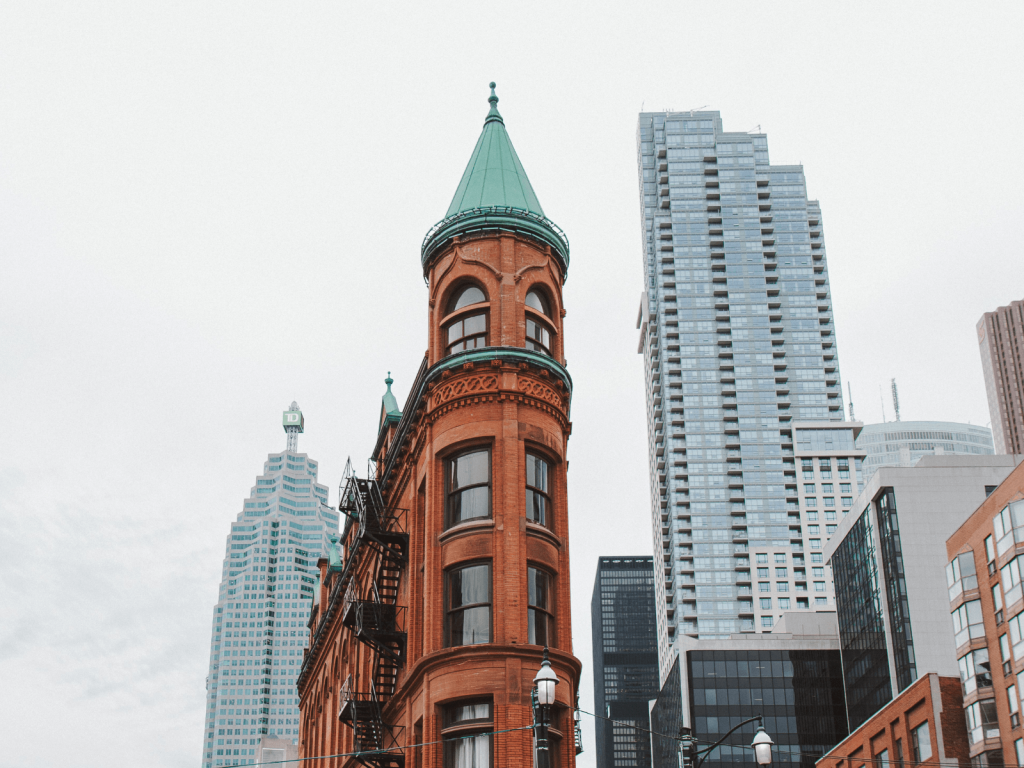 Historic red brick Gooderham Building surrounded by modern skyscrapers in downtown Toronto.