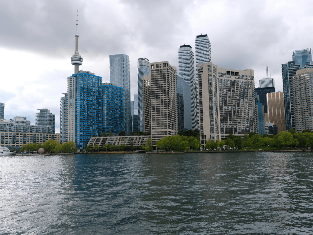 Toronto waterfront and downtown skyline beneath cloudy skies, with the CN Tower visible in the distance.