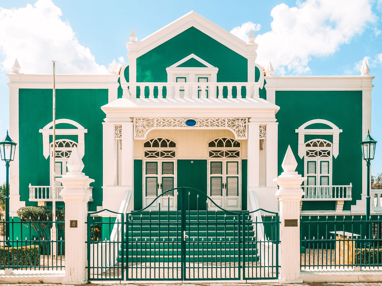 Bright green and white Dutch colonial building beneath a blue sky on one of the ABC Islands in the Caribbean.
