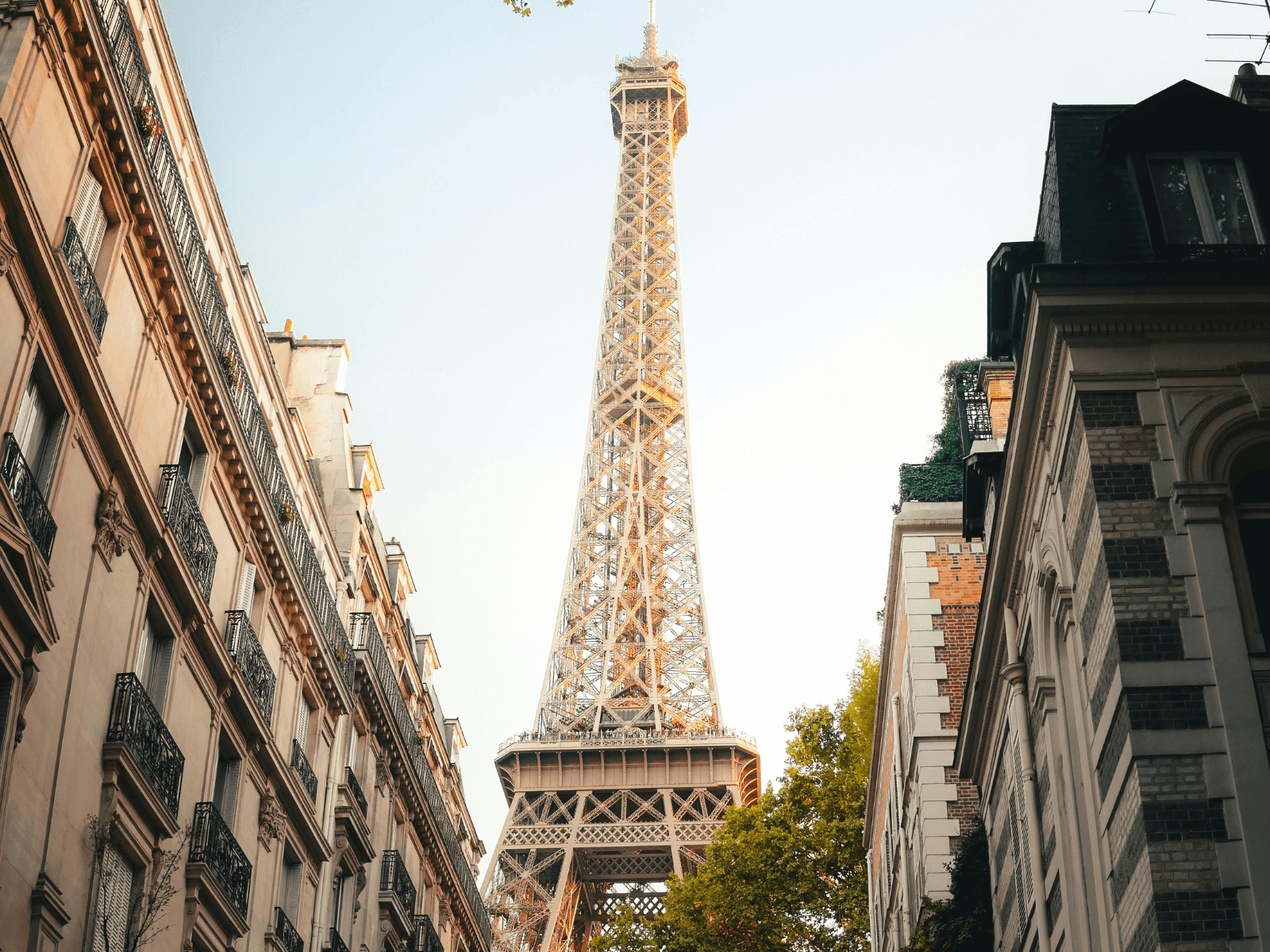Eiffel Tower rising above a Paris street lined with classic apartment buildings, showcasing one of the best Eiffel Tower photo spots in Paris.
