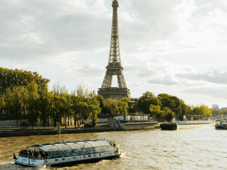Eiffel Tower rising above the Seine River with a sightseeing boat cruising past, capturing a classic view for a weekend in Paris itinerary.
