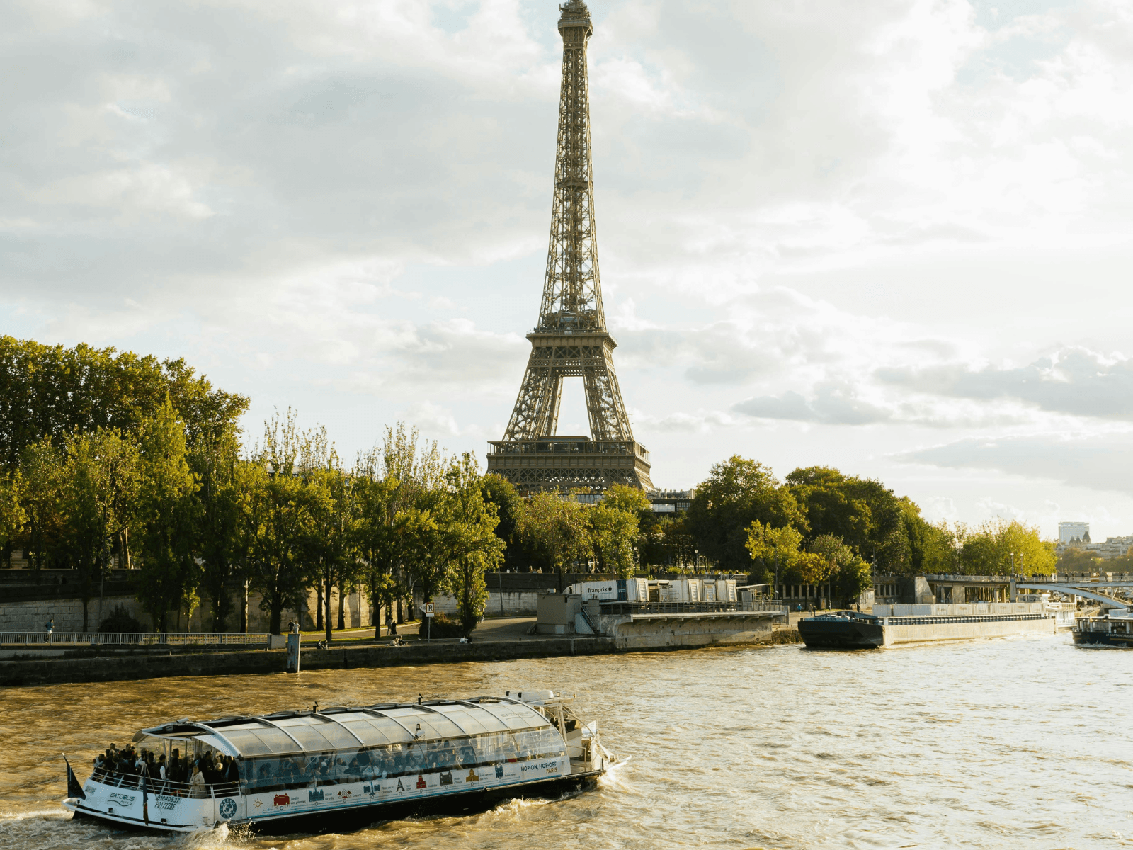 Eiffel Tower rising above the Seine River with a sightseeing boat cruising past, capturing a classic view for a weekend in Paris itinerary.