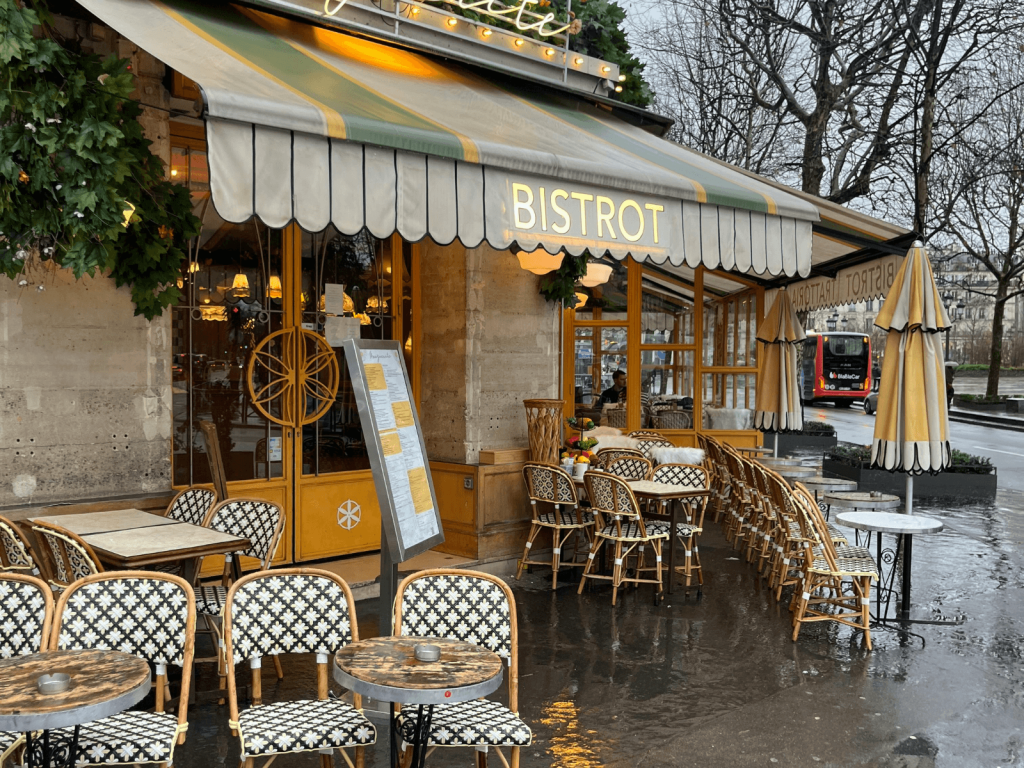 Classic Parisian bistro with sidewalk tables and café chairs on a rainy day, perfect for a weekend in Paris itinerary.