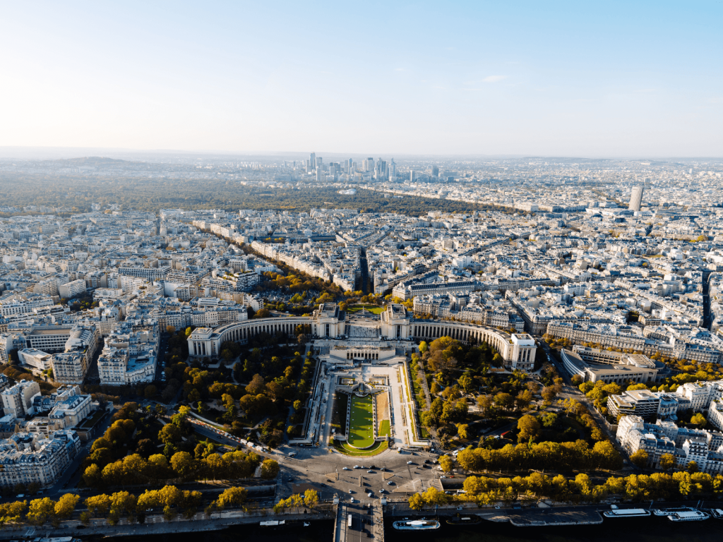 Panoramic aerial view across Paris with the Trocadéro gardens and city skyline.