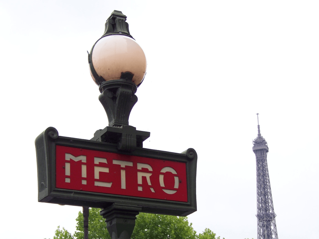 Red Paris Métro sign with the Eiffel Tower visible in the background, perfect for a weekend in Paris itinerary.