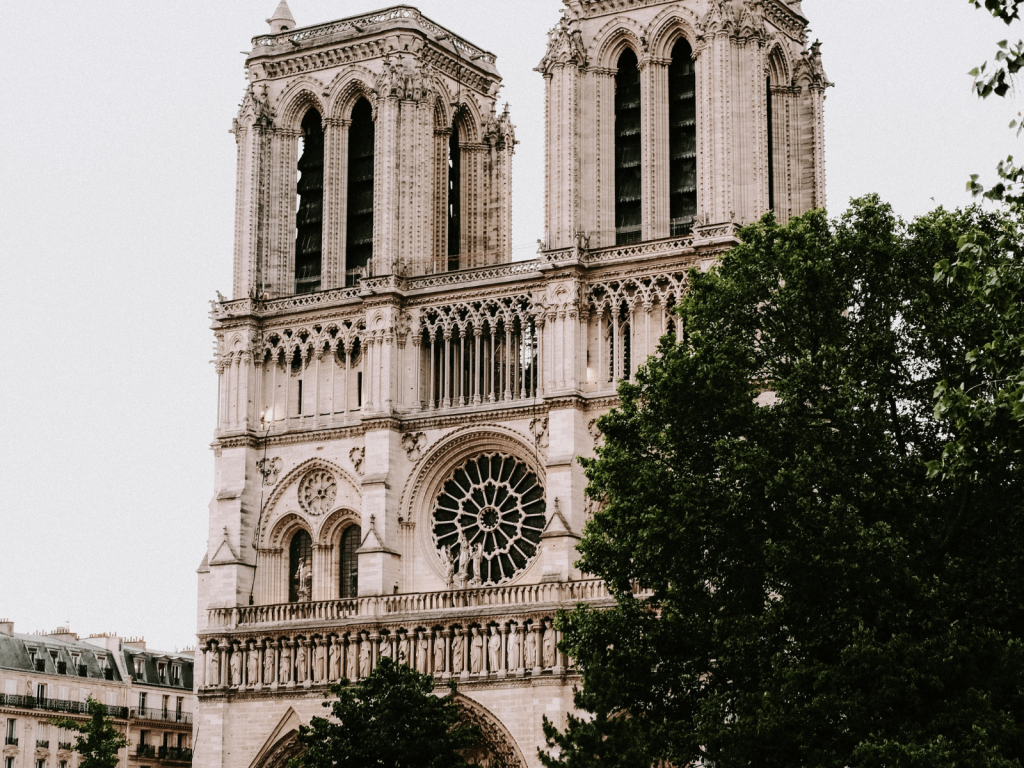 Notre Dame Cathedral in Paris framed by leafy green trees.