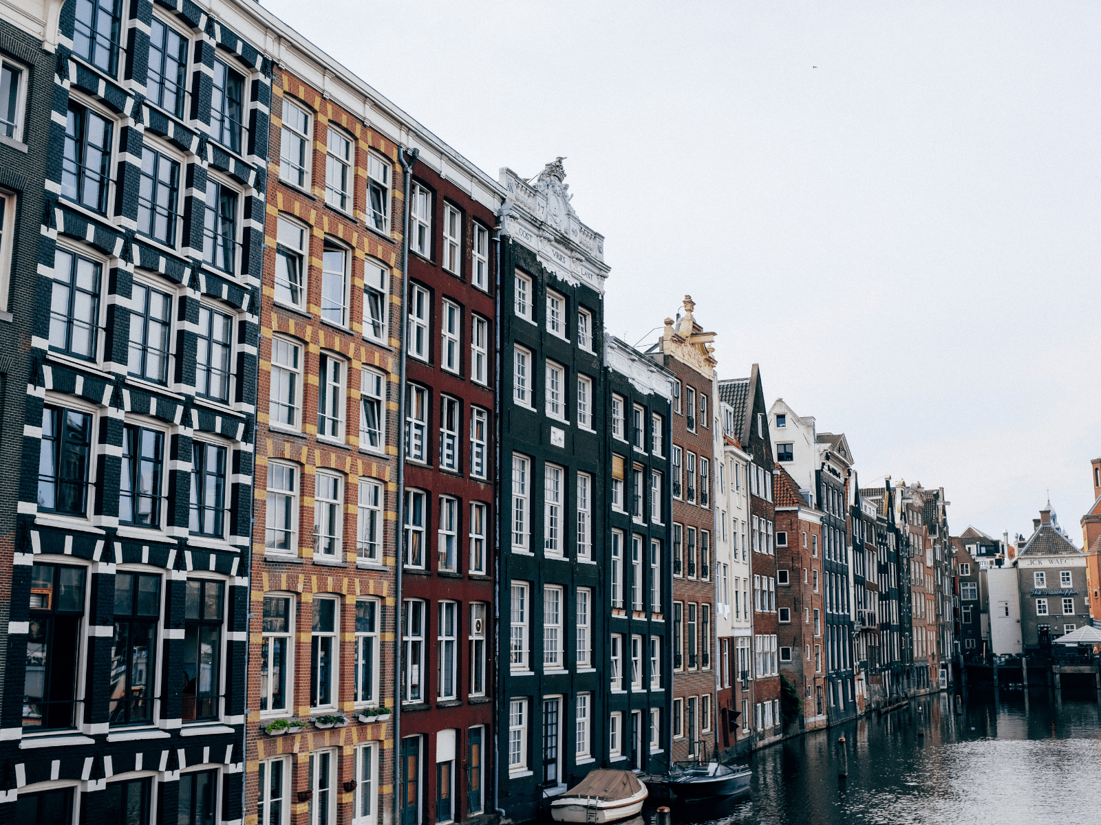 Colorful narrow canal houses lining the water in Amsterdam, a picturesque location for Amsterdam Instagram spots.