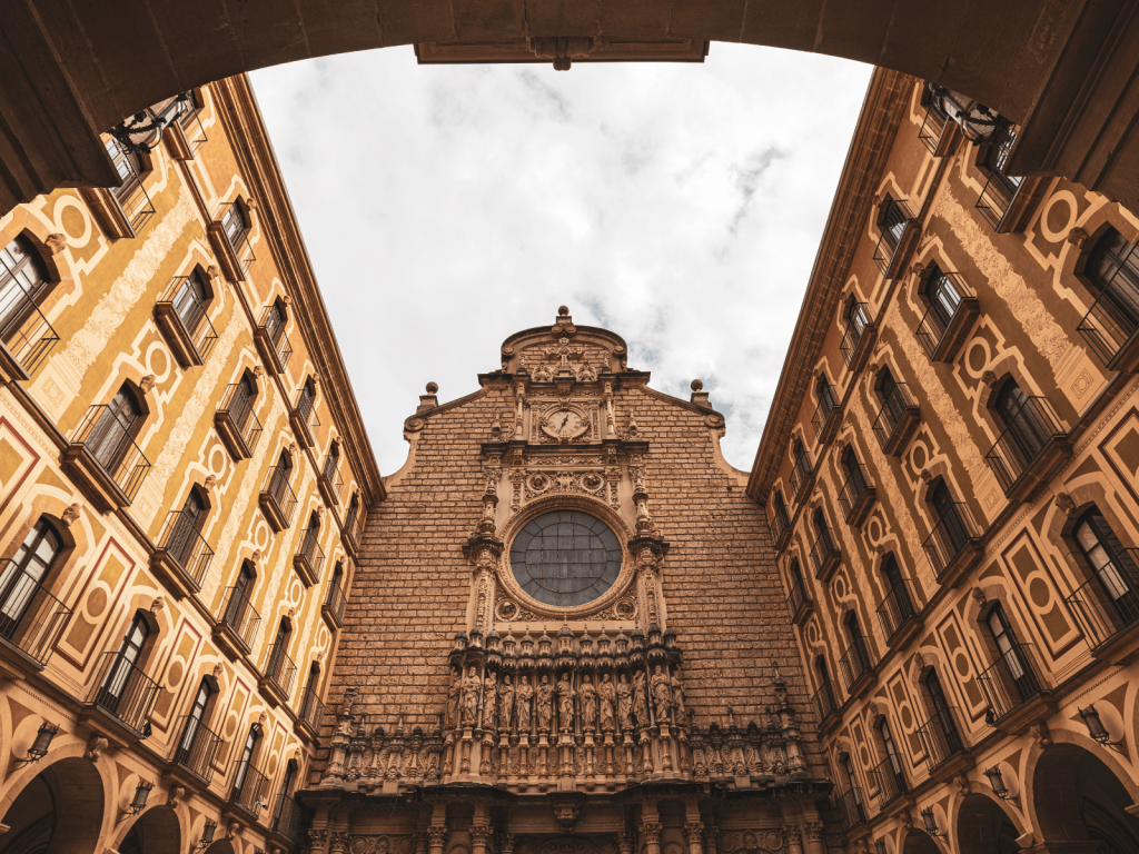Panoramic view over Barcelona’s city buildings and neighborhoods with green hills rising in the distance.