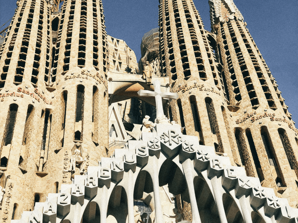 Close view looking up at the ornate stone towers and detailed facade of La Sagrada Família in Barcelona.