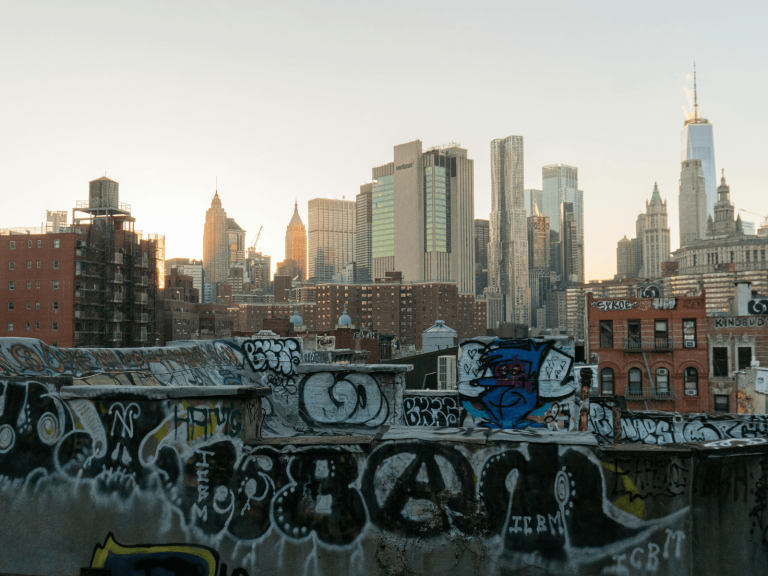 Graffiti covered rooftop overlooking the Manhattan skyline at sunset during a 2 day New York itinerary.