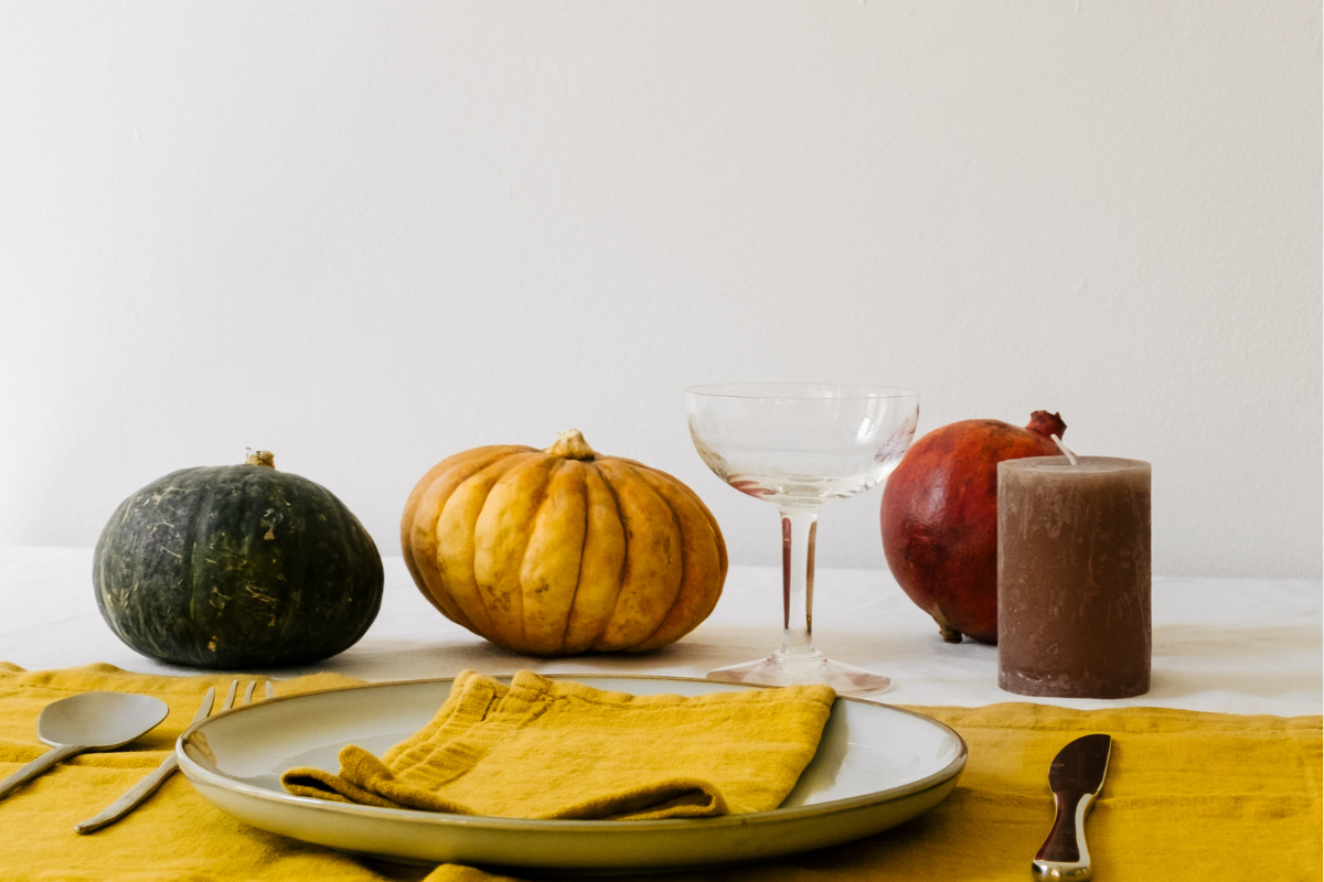 Autumn table setting with pumpkins, pomegranate, candle, and cocktail glass, perfect inspiration for fall cocktail recipes.