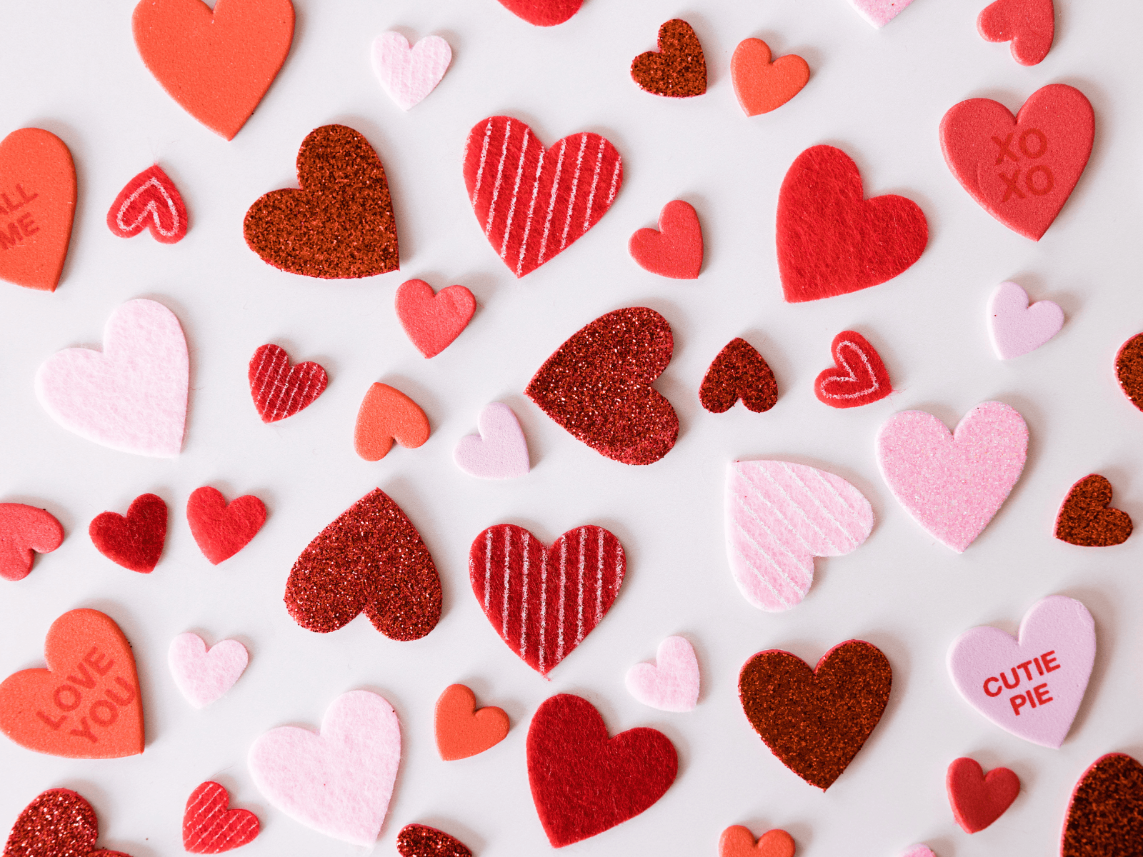 Red and pink decorative hearts with love messages arranged on a white background for Valentine captions.