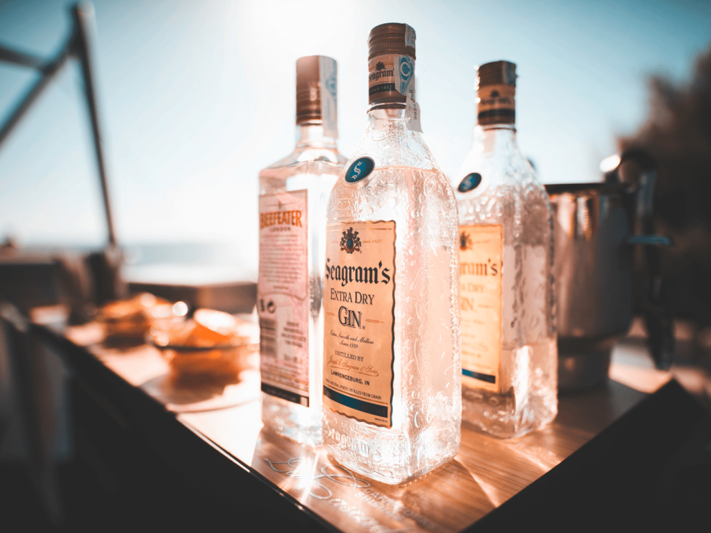 Bottles of Seagram’s Extra Dry Gin displayed on a bar counter in warm sunlight.