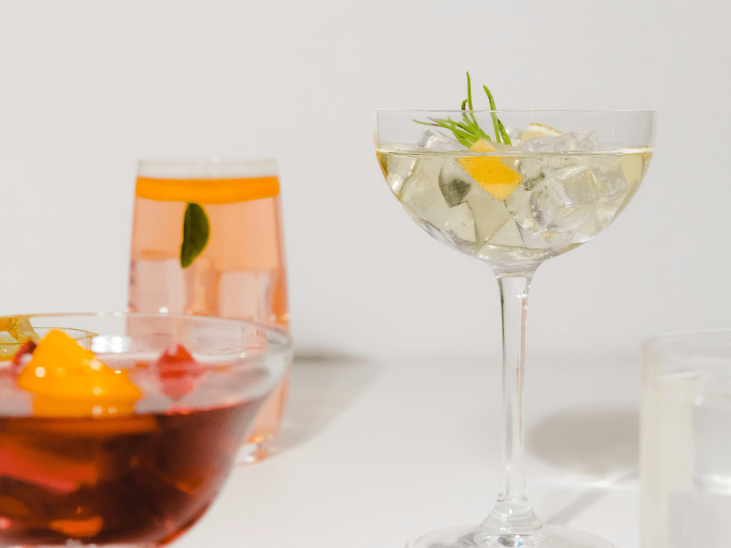Three colorful cocktails served over ice with citrus and herb garnishes, featuring stylish home bar essentials for making drinks at home.