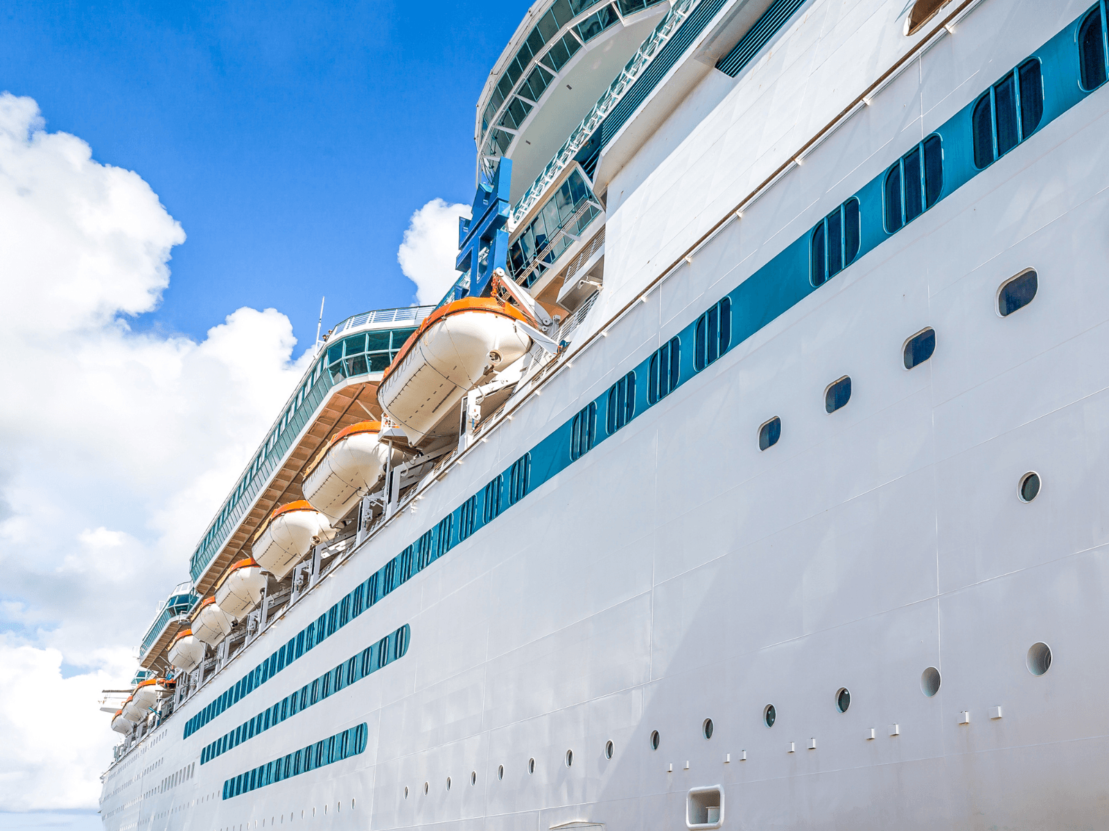 Close up view of a large white cruise ship with rows of windows and lifeboats under a bright blue sky, representing the best European cruise options.