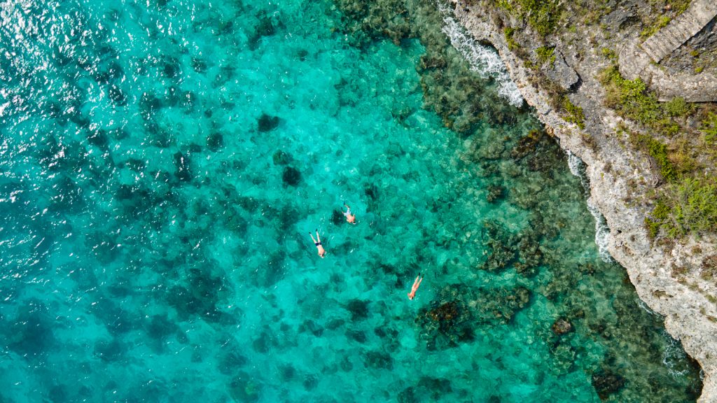 Aerial view of swimmers at a beach in Bonaire in the ABC Islands one of the best babymoon destinations in the Caribbean. 