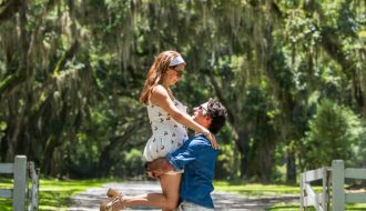 A couple enjoying a romantic moment under the canopy of moss-covered oak trees on a sunlit path — a dreamy stop during 2 days in Savannah, Georgia.