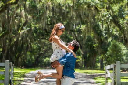 A couple enjoying a romantic moment under the canopy of moss-covered oak trees on a sunlit path — a dreamy stop during 2 days in Savannah, Georgia.