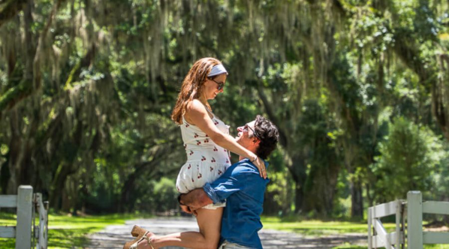 A couple enjoying a romantic moment under the canopy of moss-covered oak trees on a sunlit path — a dreamy stop during 2 days in Savannah, Georgia.