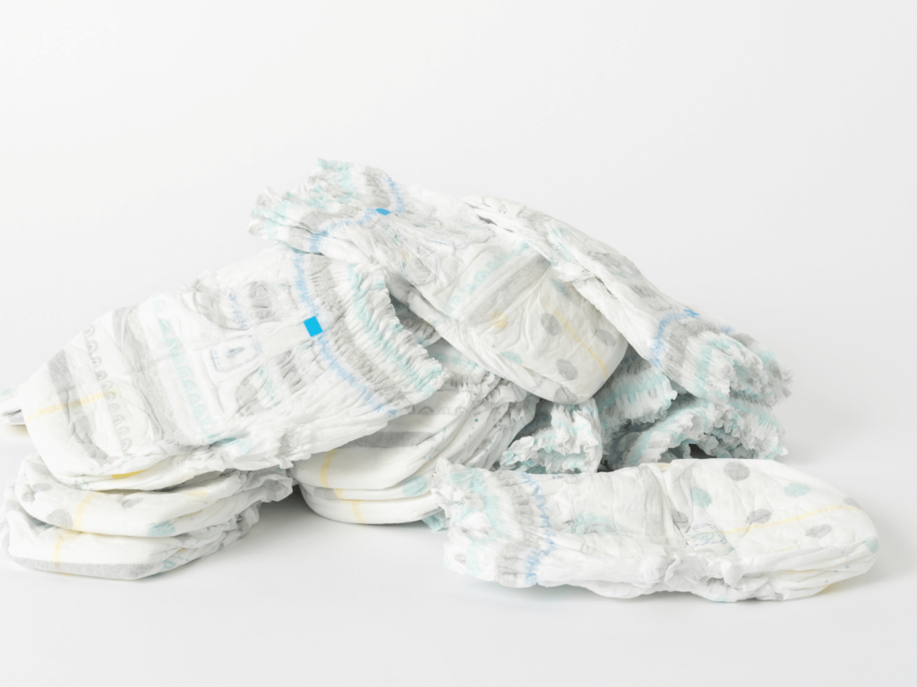 Close-up of a stack of disposable newborn diapers on a white background, showing a key item every parent needs for quick changes on the go.