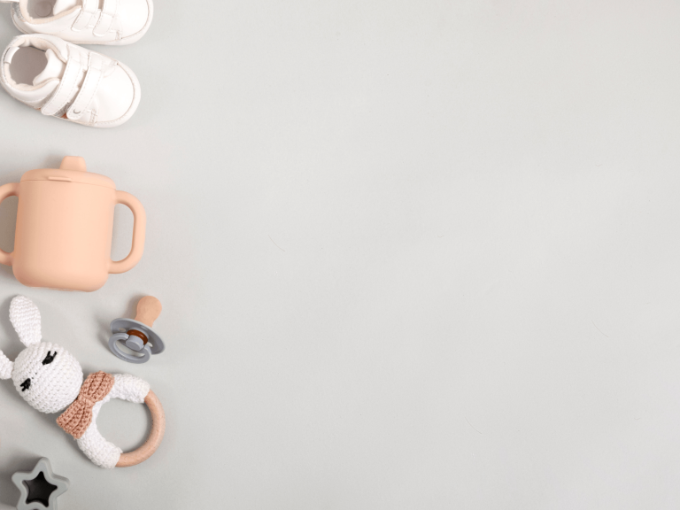 Baby travel essentials including shoes, sippy cup, pacifier, and bunny toy for a baby travel packing list.