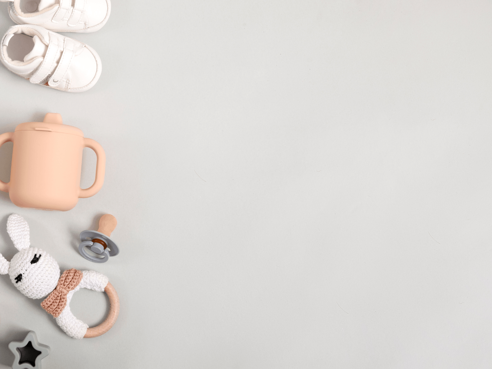 Baby travel essentials including shoes, sippy cup, pacifier, and bunny toy for a baby travel packing list.