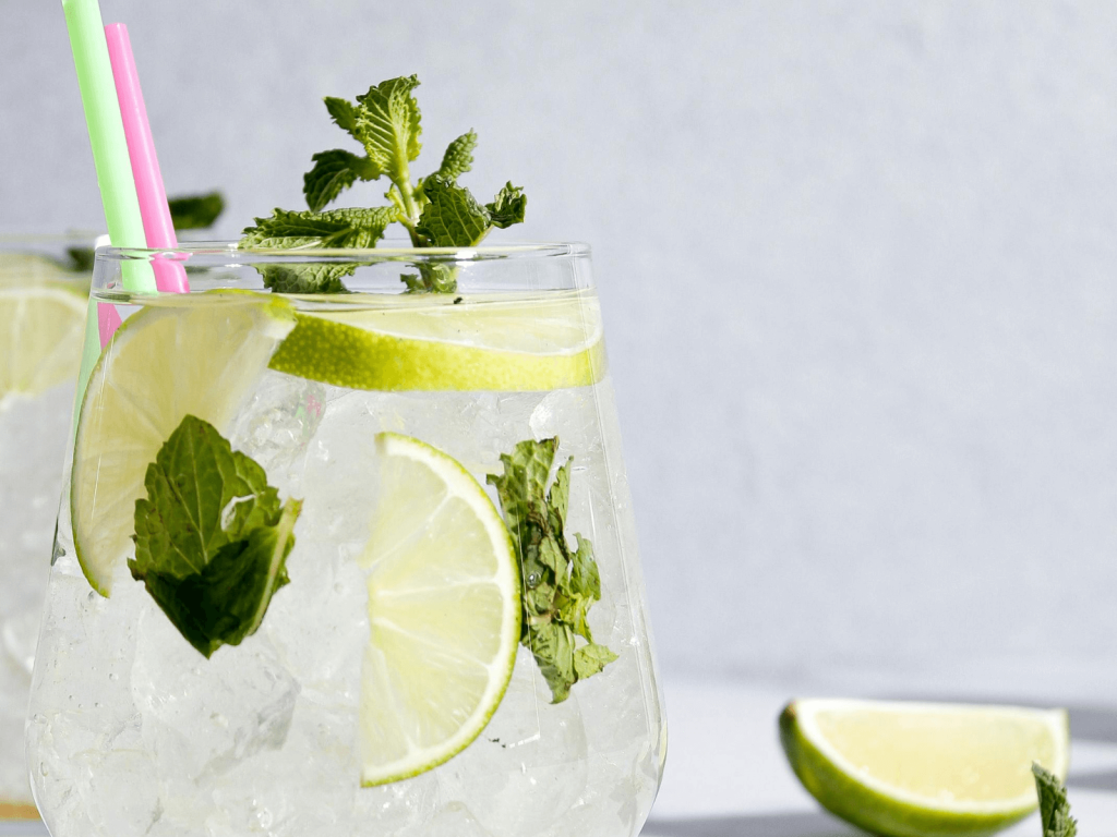Mojito cocktail in a stemless glass filled with crushed ice, garnished with lime slices and fresh mint, with colorful straws, a refreshing example of cocktails around the world.