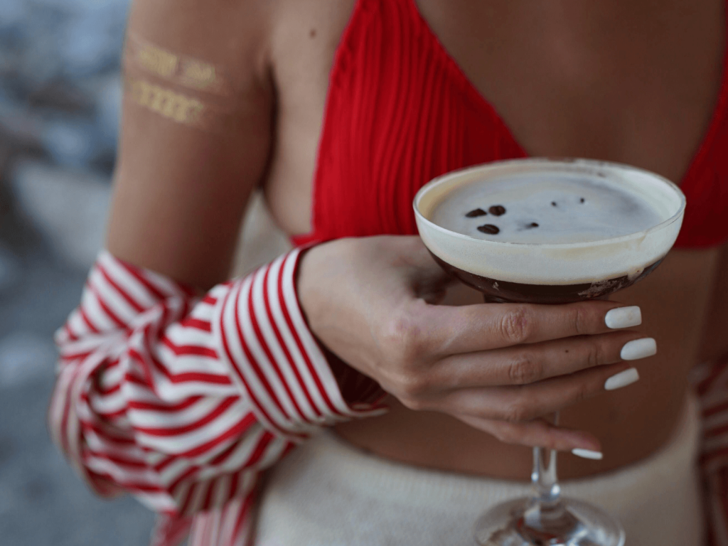 Woman holding an espresso martini in a coupe glass topped with coffee beans, a stylish example of cocktails around the world.