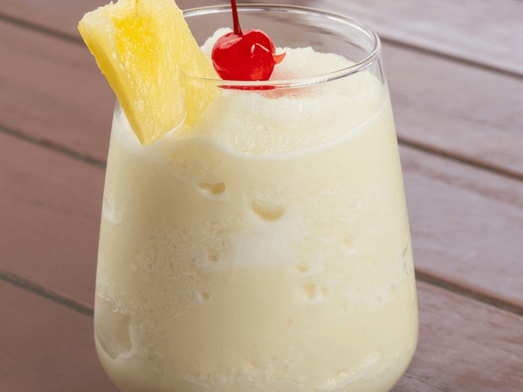 Frozen piña colada garnished with a pineapple wedge and red cherry.