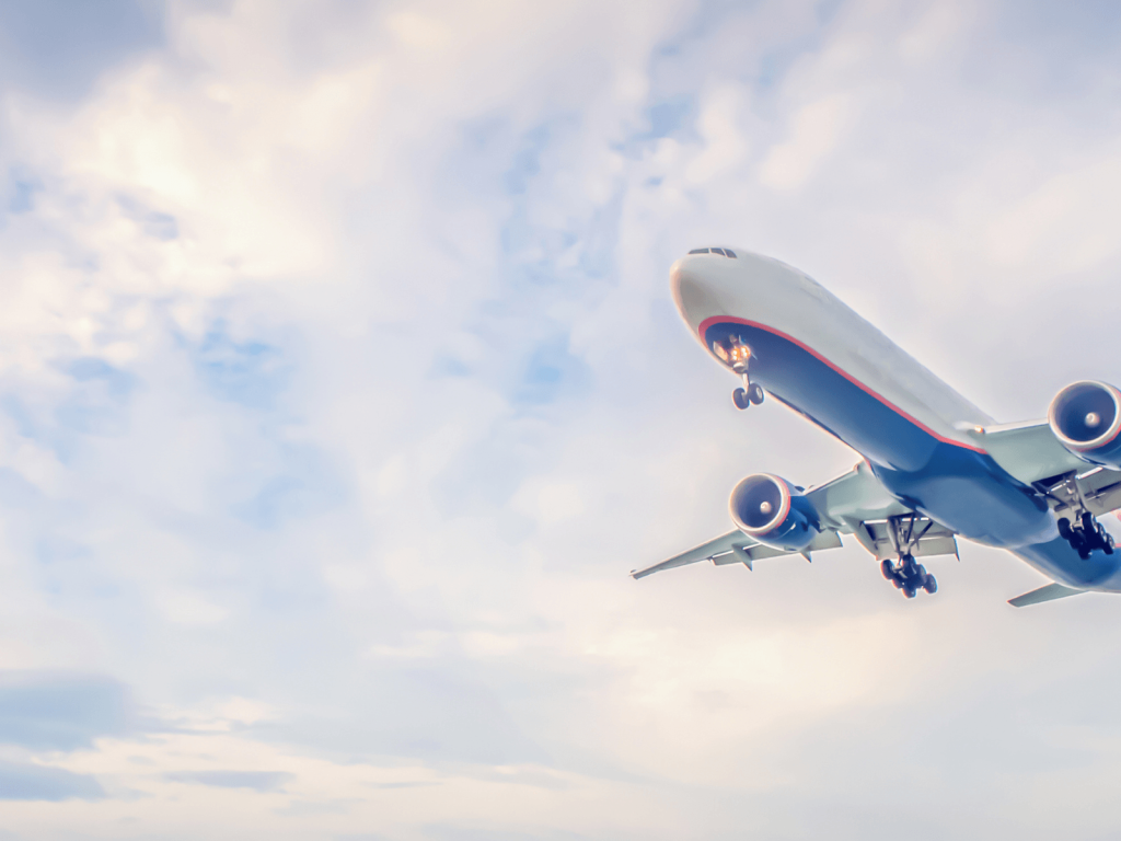 Airplane flying through a cloudy sky, representing air travel and planning ahead when flying with a baby.