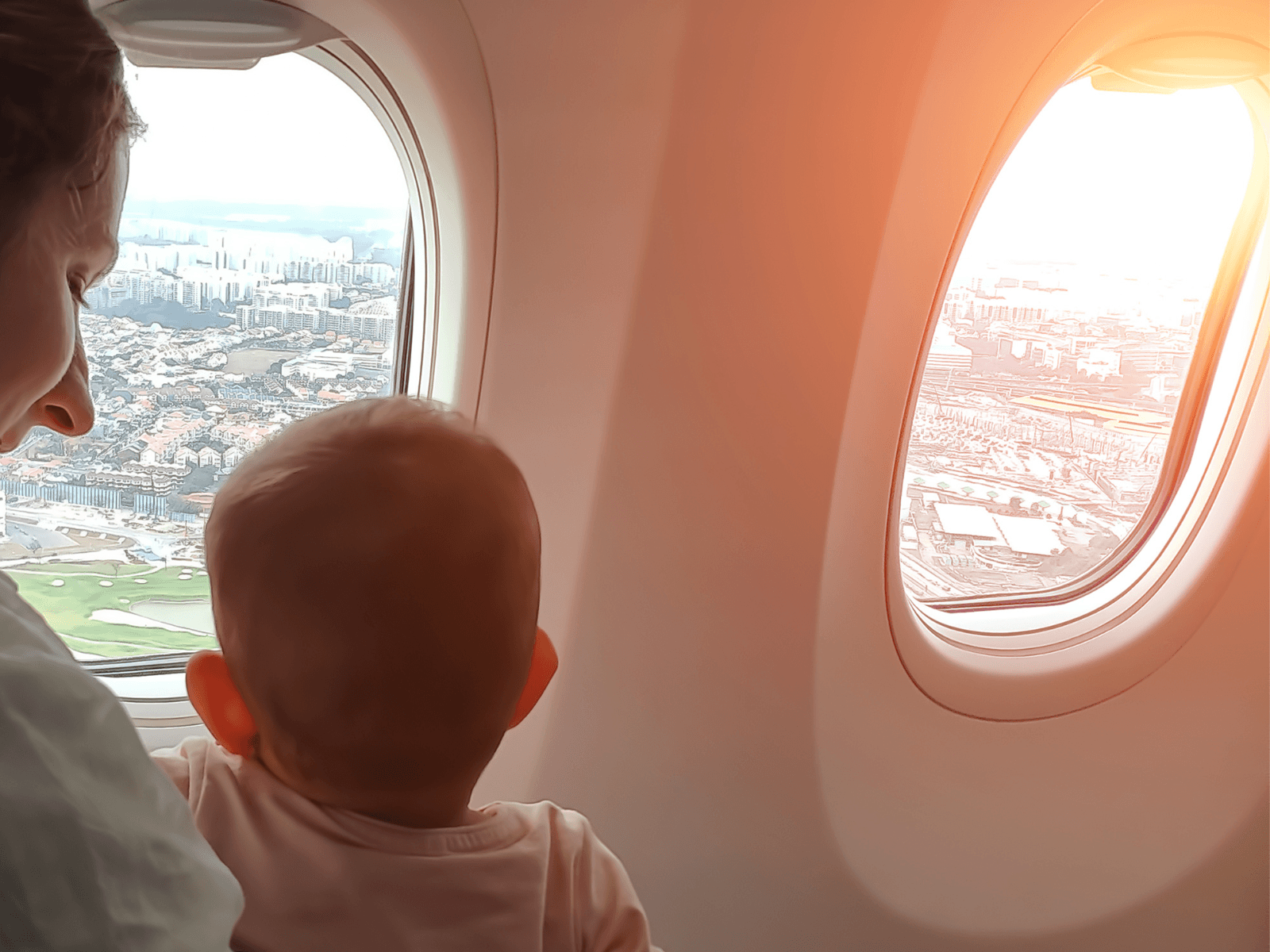 Mother and baby looking out an airplane window, used for a post about tips when flying with a baby.