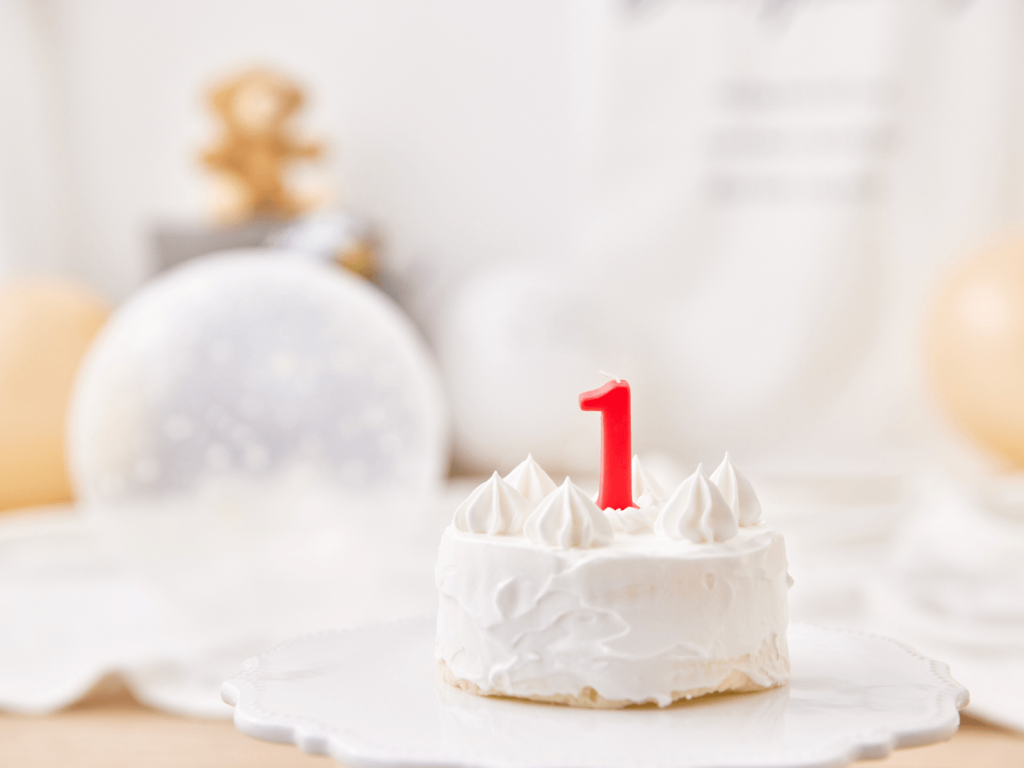 Small white birthday cake topped with a red number one candle, perfect for celebrating a baby and sharing 1st birthday wishes.
